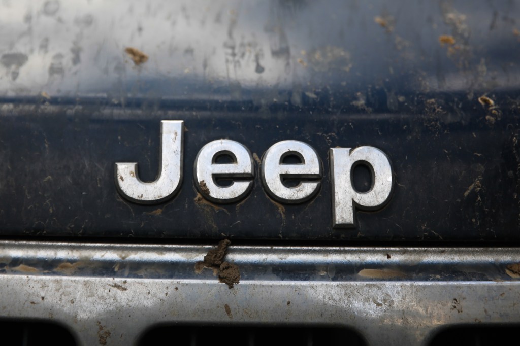 Close-up of the Jeep logo on the front-end of a muddy SUV