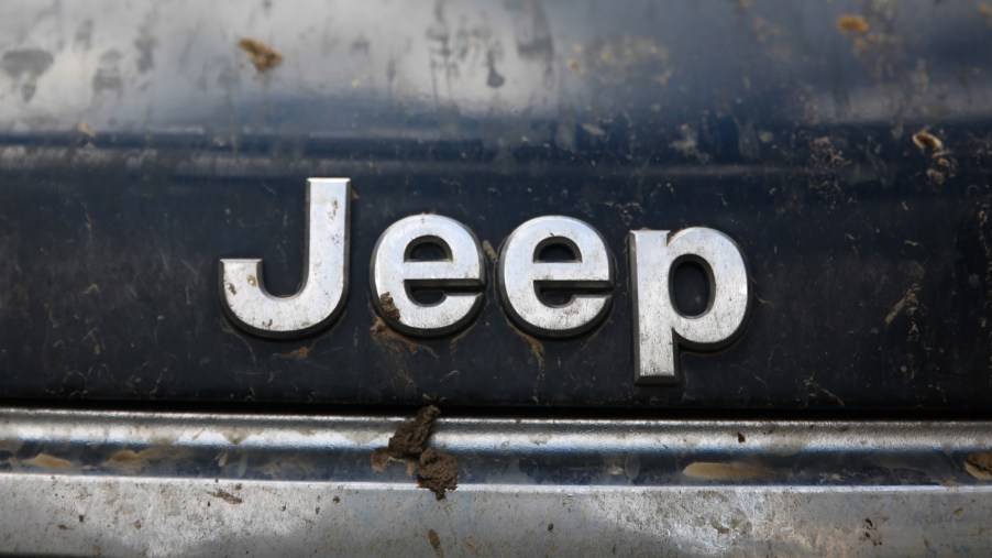 Close-up of the Jeep logo on the front-end of a muddy SUV