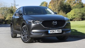 A black Mazda CX-5 parked and on display with trees in the background.