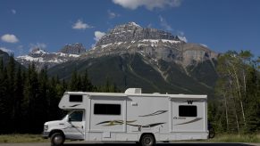 A motorhome RV camper parked on a road in front of a mountain