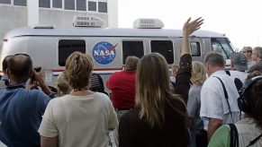An employee of NASA waves to the crew of the Space Shuttle Atlantis as they leave