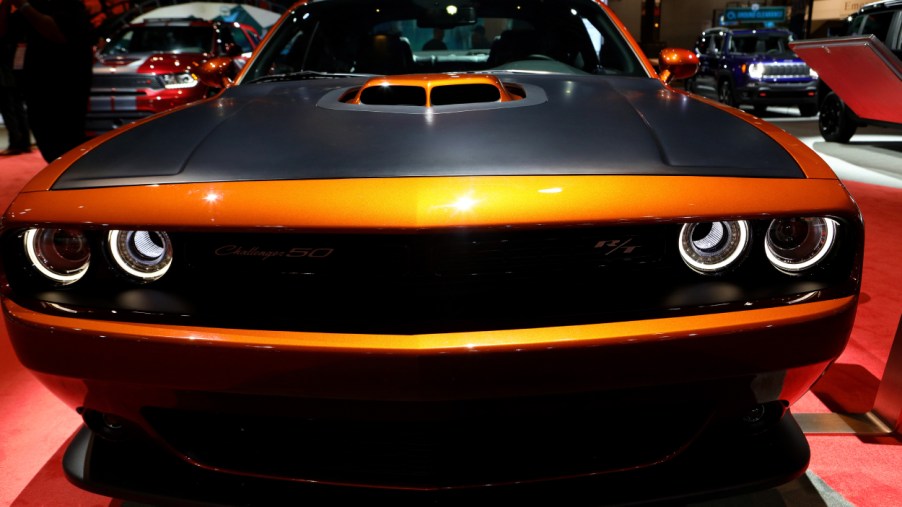 An orange Dodge Challenger on display at an auto show