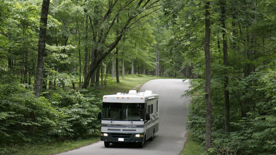An RV driving down a road in the woods