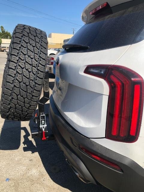 A white Kia Telluride with Rigid Armor's hitch-mounted spare tire carrier