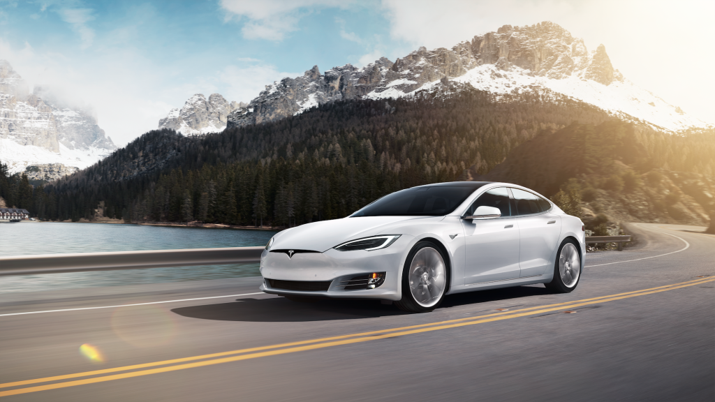 White Tesla Model S electric car driving through the mountains