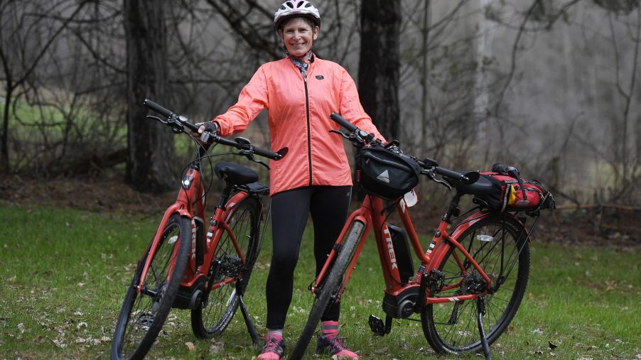 A woman posing with two electric bikes