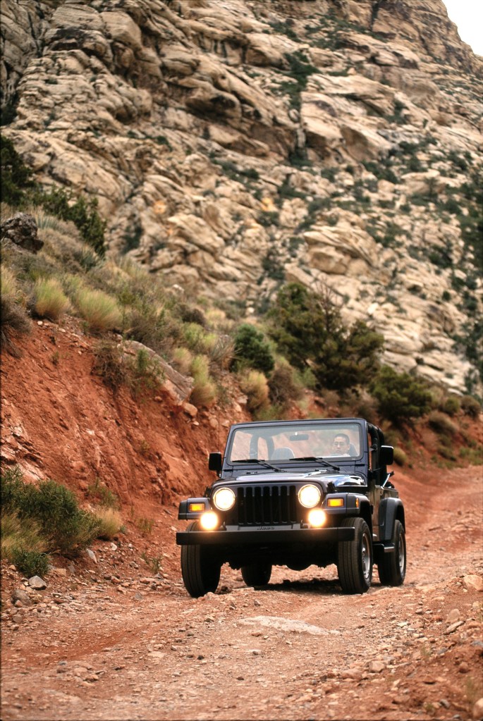 Jeep Wrangler off-road in a rocky western setting.