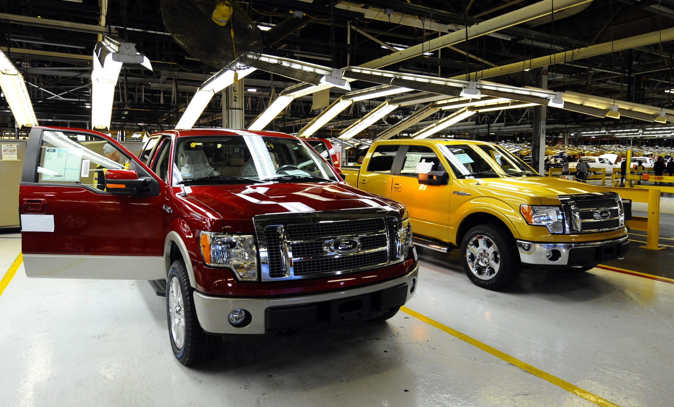 Two Ford F-150 trucks next to an assembly line