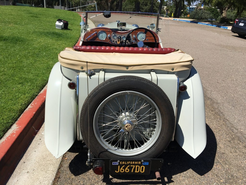 The rear view of a gray 1949 MG TC EXU with a view of its red-leather interior