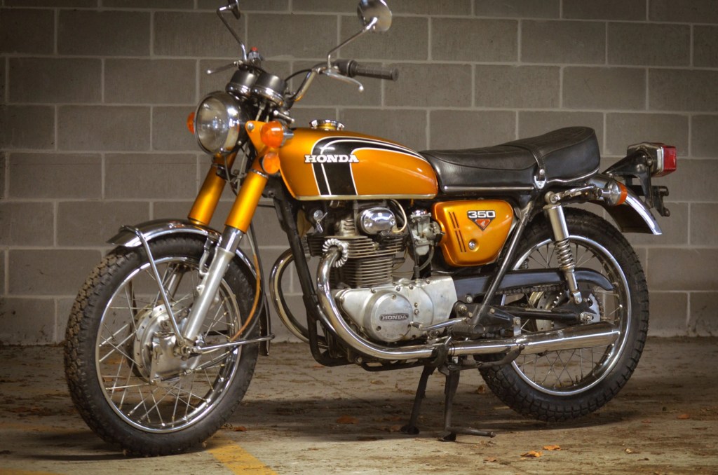 An orange 1972 Honda CB350 in a parking garage