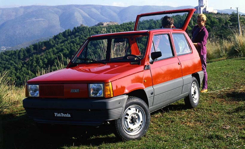 A red 1980 Fiat Panda parked on a grassy hill with its hatchback raised