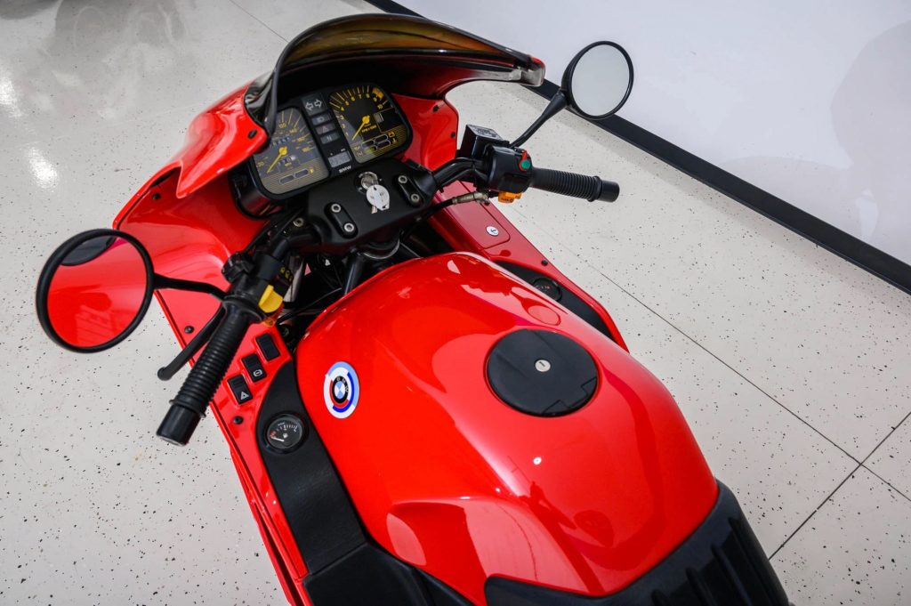 A close-up of a red-and-yellow 1990 BMW K1's dash and handlebars