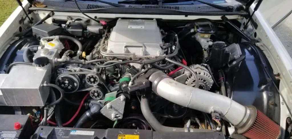 The engine bay reveals a custom crate engine for a Cadillac Fleetwood Brougham