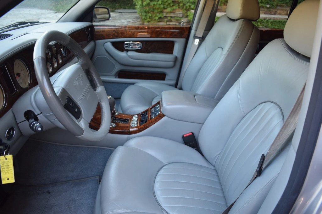 The gray-leather-upholstered front seats and wooden dashboard of a 2001 Bentley Arnage Red Label