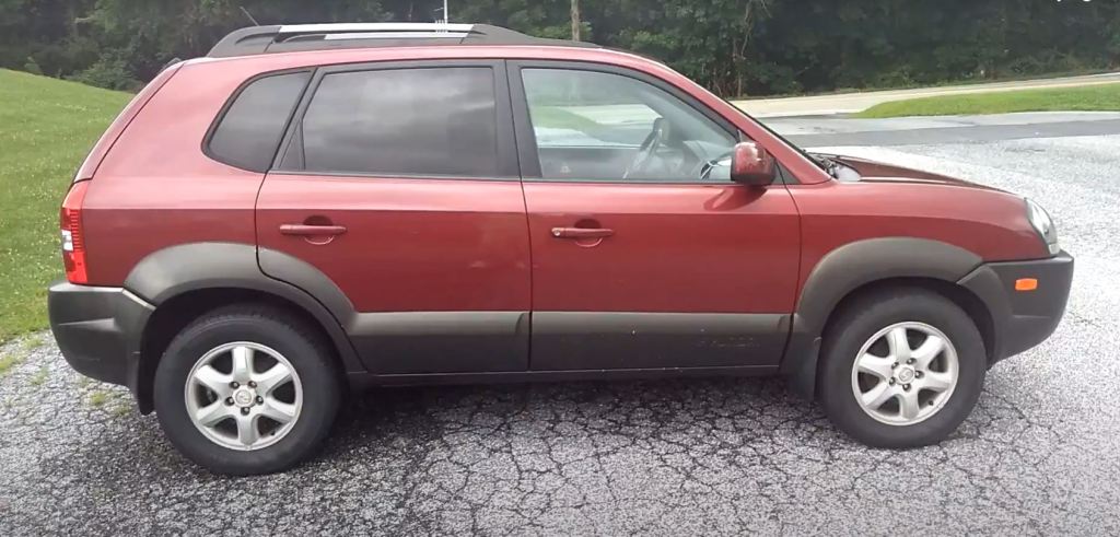 The passenger side view of a burgundy and gray 2005 Hyundai Tucson