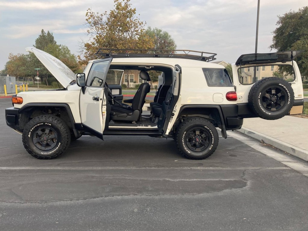 The side view of a modified white 2008 Toyota FJ Cruiser Trails Team Edition with its doors open