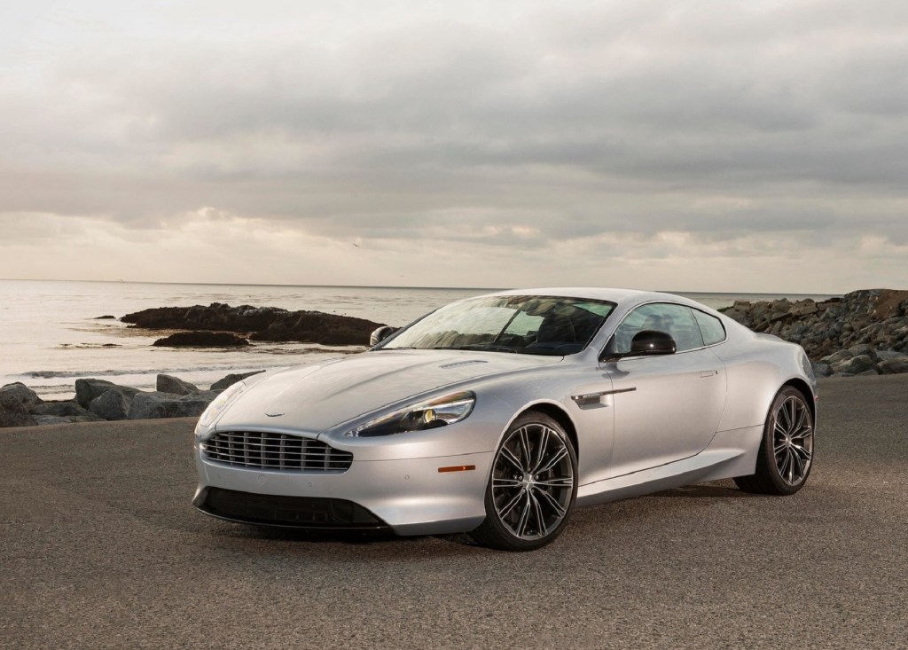 A 2013 Aston Martin DB9 parked in front of a rocky ocean beach