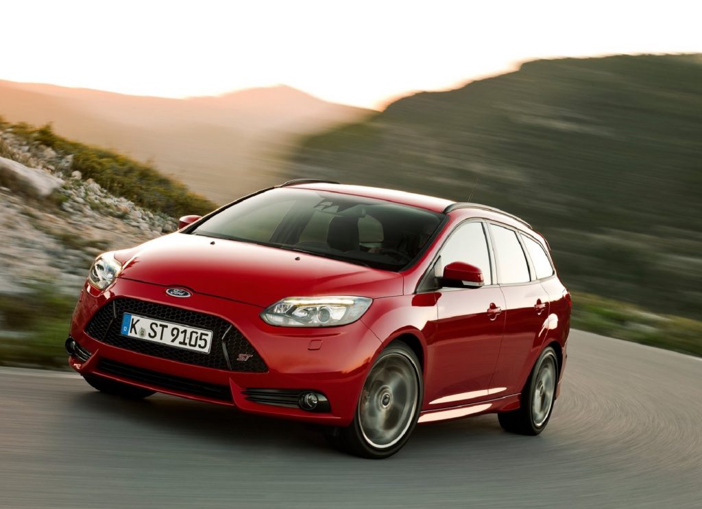 A red 2013 Ford Focus ST drives around a curving road