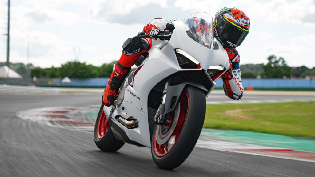 A red-clad rider takes a white 2020 Ducati Panigale V2 on a racetrack