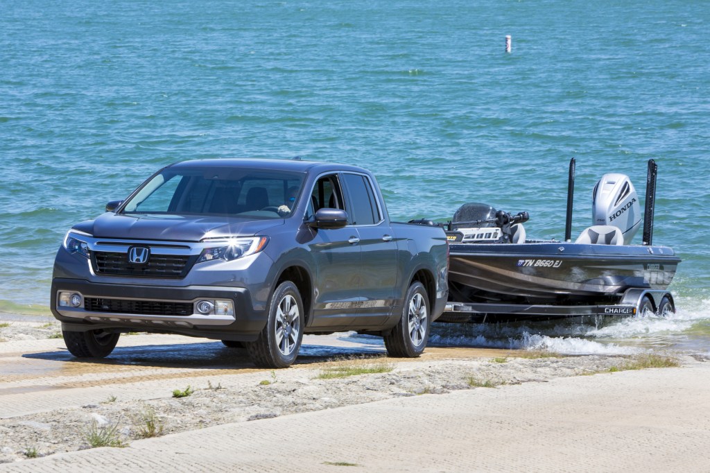 A 2020 Honda Ridgeline towing a small boat near the water