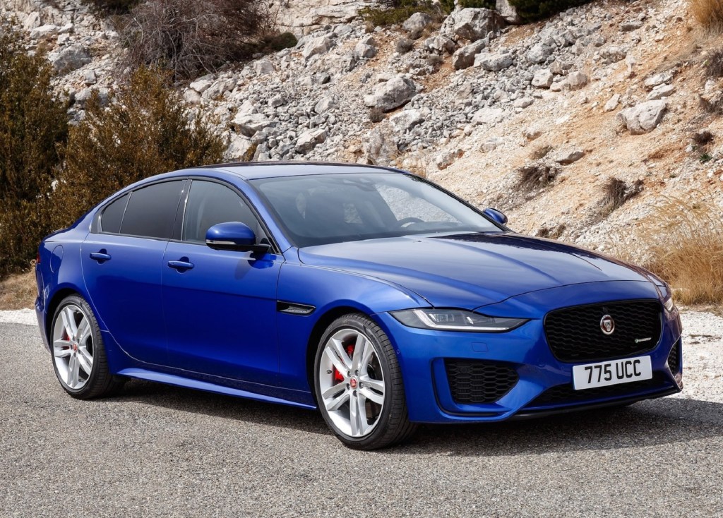 A blue 2020 Jaguar XE in front of a rocky hill