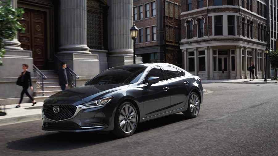 The 2020 Mazda6 driving down a city street with buildings in the background