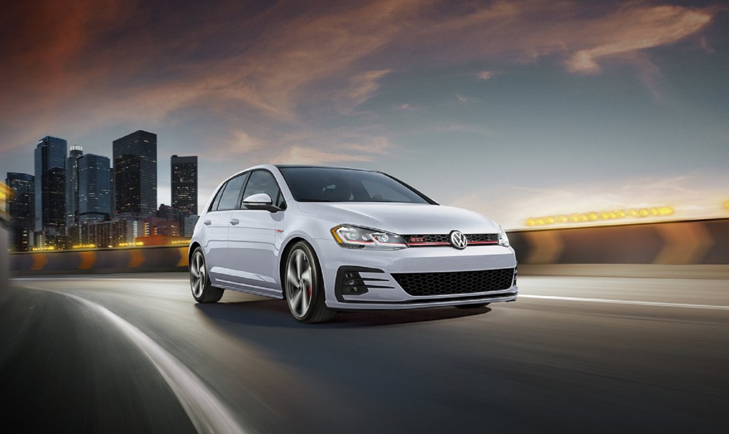 A white Volkswagen Golf GTI leaves the city.