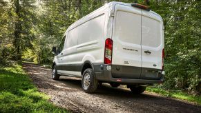 A white 2021 Ford Transit AWD with the Adventure Prep Package drives up a forest hill