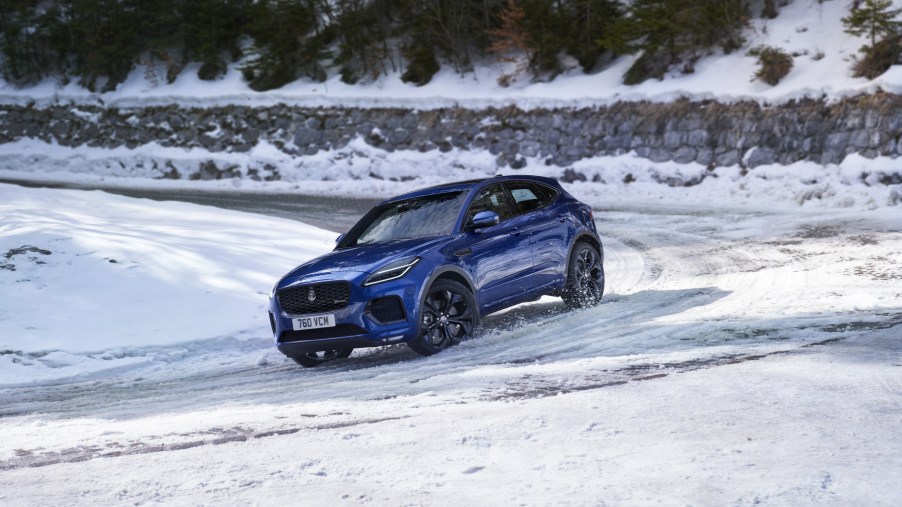 A blue 2021 Jaguar E-Pace driving on a snow-covered road.