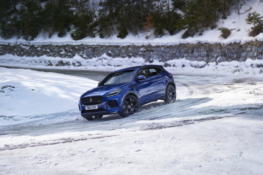 A blue 2021 Jaguar E-Pace driving on a snow-covered road.