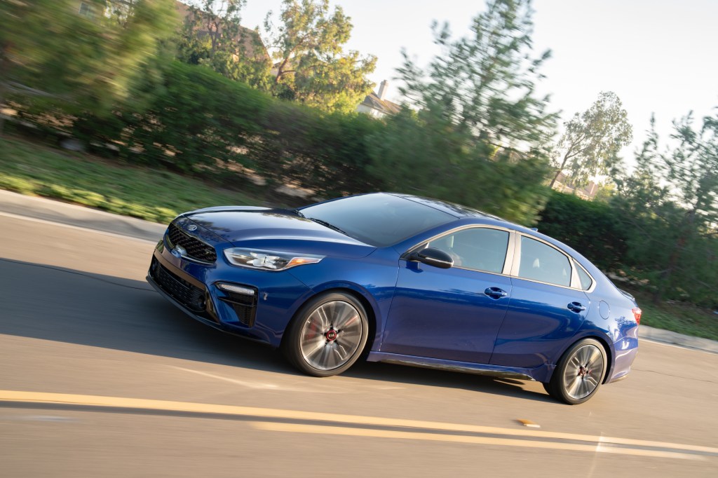 A blue 2021 Kia Forte displays its commuter car prowess while driving on the highway