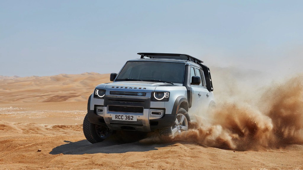 A silver 2021 Land Rover Defender 110 drives through the desert