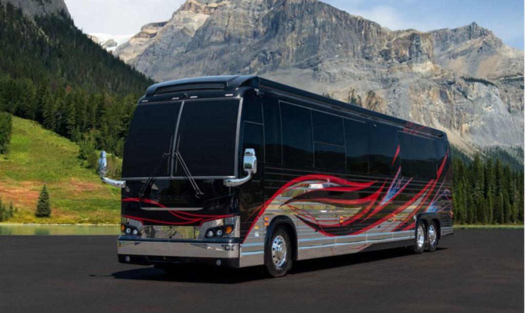 A black and chrome bus sized RV sits in the foreground. Mountains are in the background. 