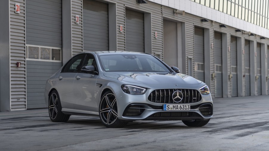 A press image of a silver 2021 Mercedes AMG E63 S sedan parked in front of an industrial building