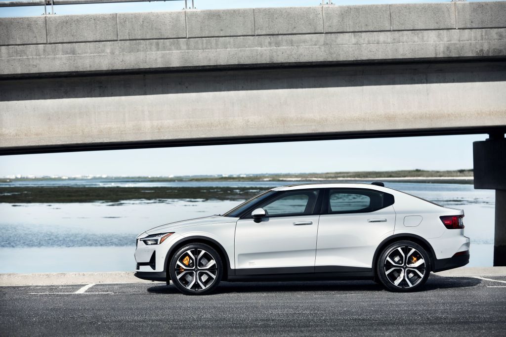 The side view of a white 2021 Polestar 2 Launch Edition by a concrete bridge