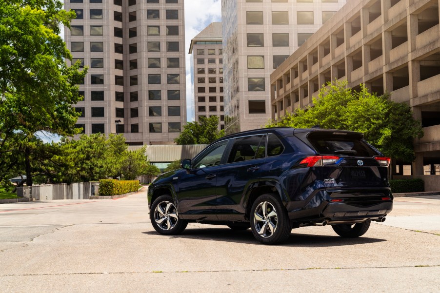 A blue 2021 Toyota RAV4 Prime facing away while parked in the middle of a city.