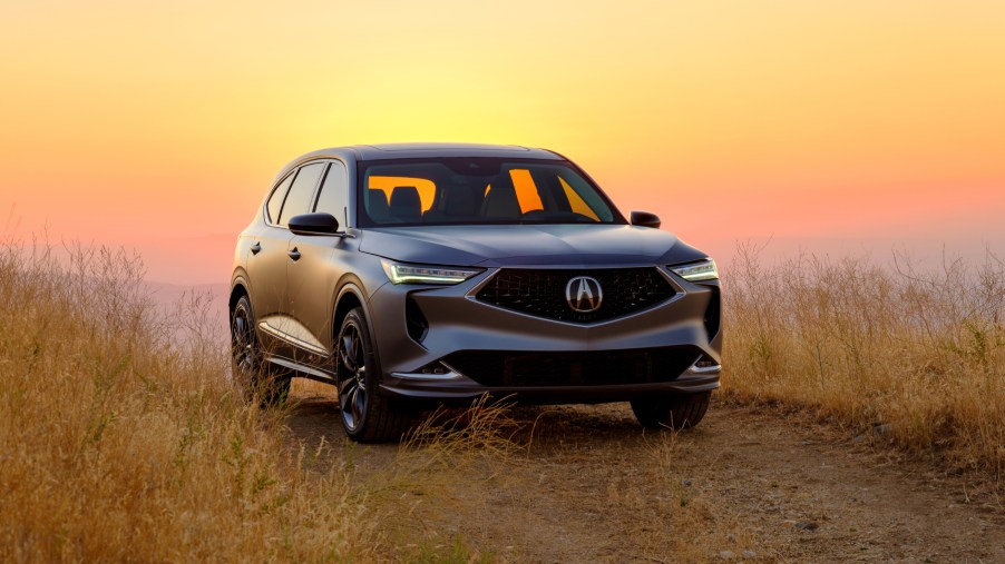 The 2022 Acura MDX prototype parked in a patch of grass with the setting sun in the background