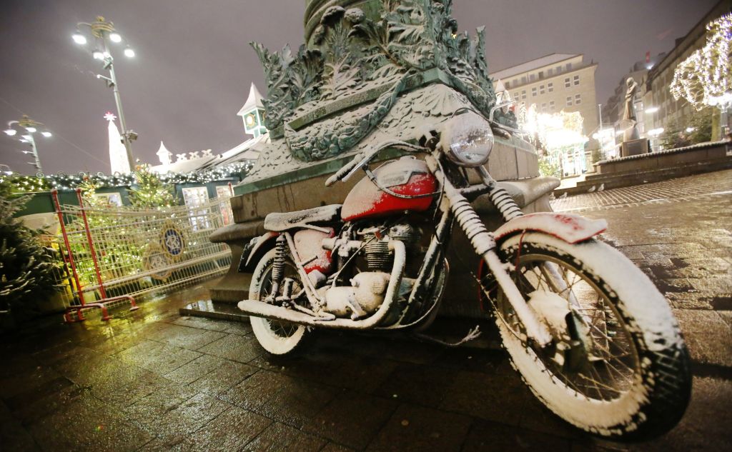 A red motorcycle covered in snow at a winter market