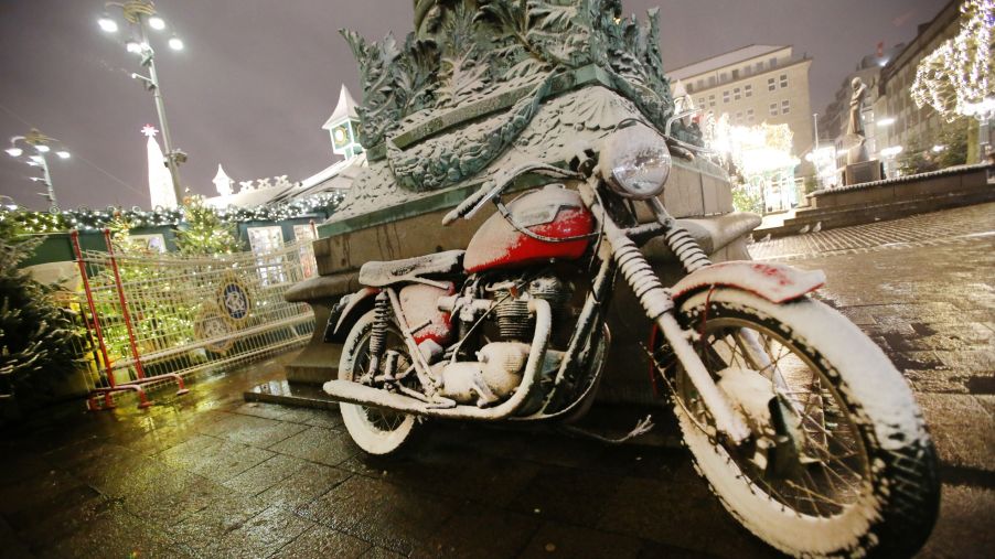 A red motorcycle covered in snow at a winter market