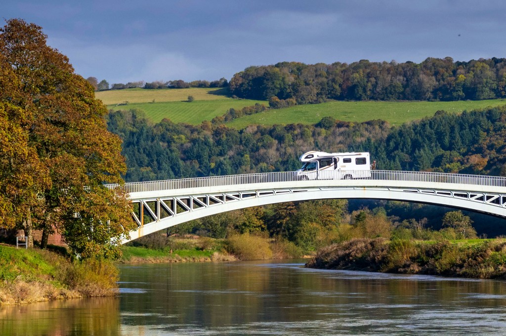 A camper van travels from the England to Wales over Bigsweir Bridge which spans the River Wye between Wales and England