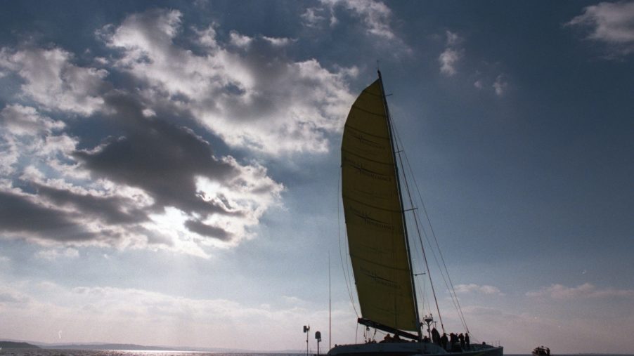 A catamaran sailboat seen sailing around sunset