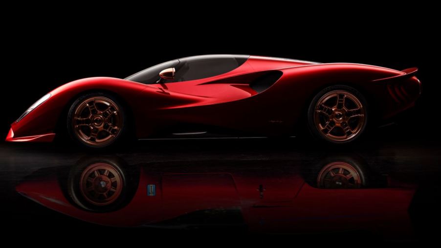 A red, low-slung, curvy sports car sits against a black background. The De Tomaso P72