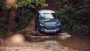 An image of a Land Rover Defender off-roading through some mud.