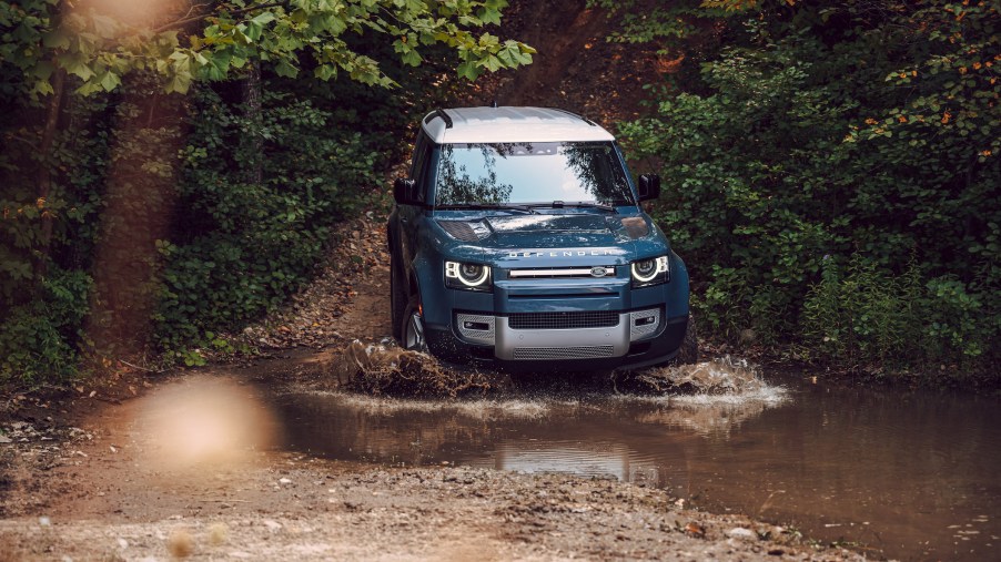 An image of a Land Rover Defender off-roading through some mud.