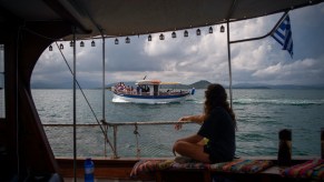 Tourists take part in a dolphin watching tour from a boat in the Amvrakikos gulf
