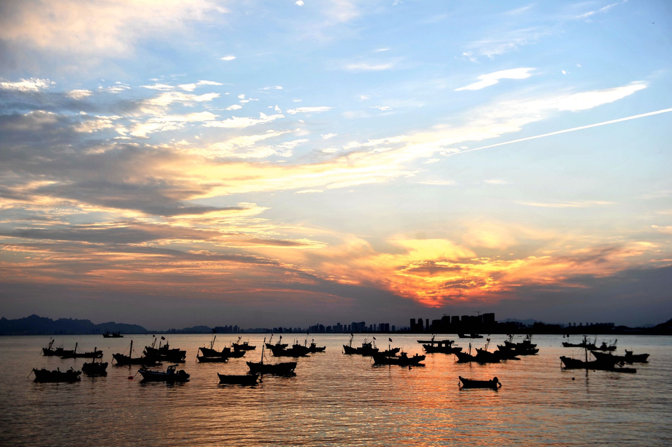 Returning fishing boats moor under the sunset in Qingdao, Shandong Province, China