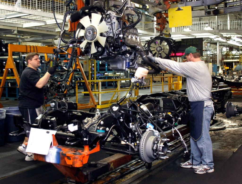 Workers assemble an engine at a GMC factory