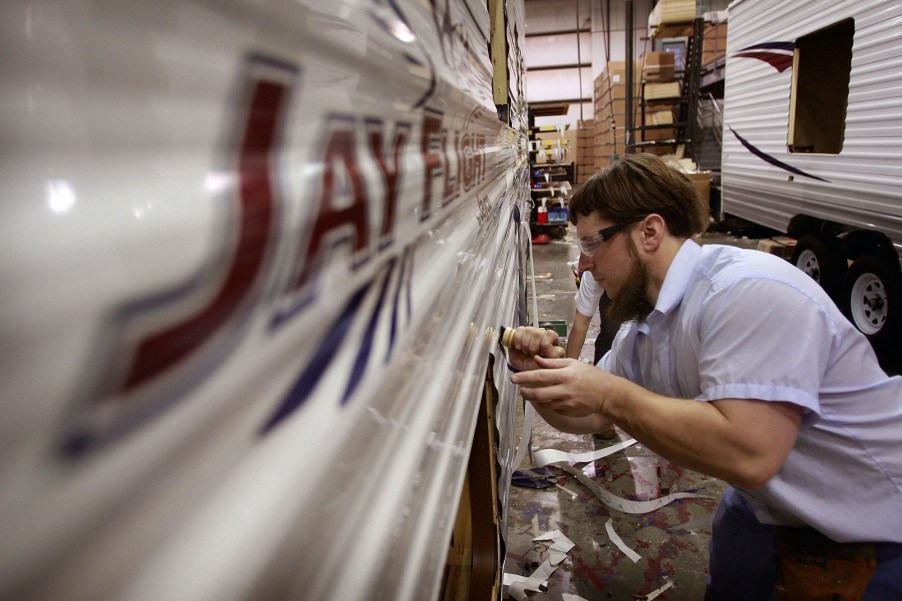 A worker at Jayco, Inc., the country's third largest maker of recreational vehicles, puts decals on a Jay Flight travel trailer