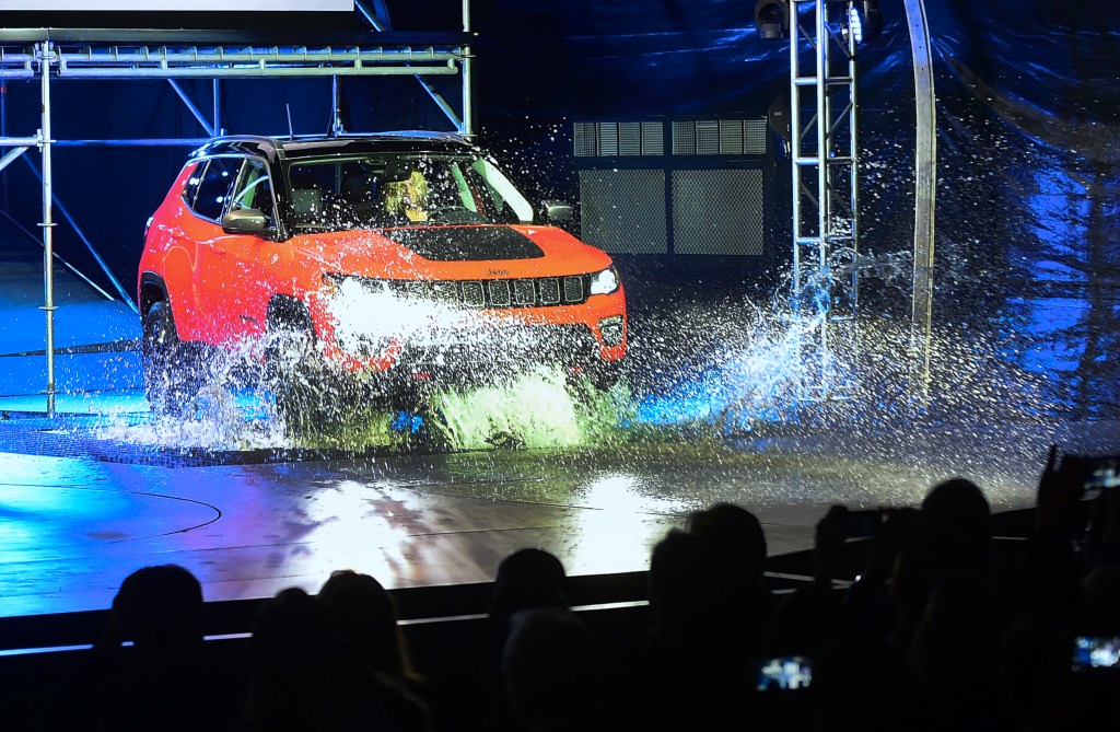 A red Jeep Compass puts its capability on display by driving into water
