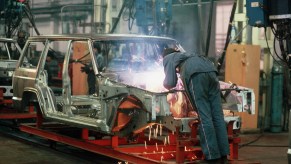 A welder in a Jeep factory goes to work on a frame